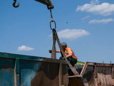 Dnepropetrovsk, Ukrayna - 05.28.2021: Çöp konteynerlerini vinç kullanarak bir kamyona yüklemek. Slinger çalışıyor..