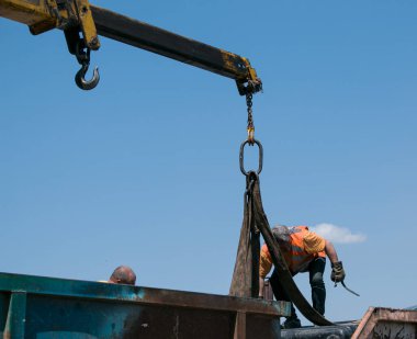 Dnepropetrovsk, Ukrayna - 05.28.2021: Çöp konteynerlerini vinç kullanarak bir kamyona yüklemek. Slinger çalışıyor..