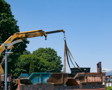 Çöp konteynırlarını vinç kullanarak bir kamyona yüklüyorlar. Slinger çalışıyor..