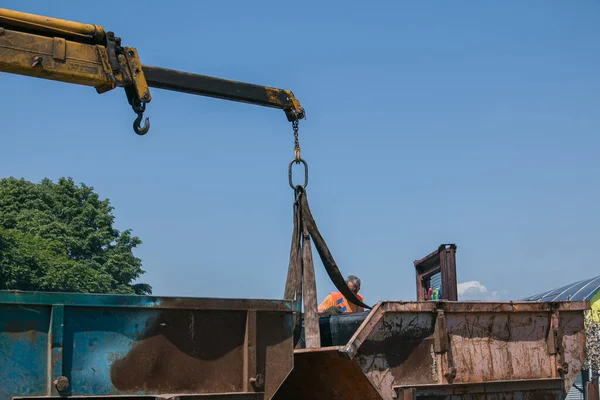 Dnepropetrovsk, Ukrayna - 05.28.2021: Çöp konteynerlerini vinç kullanarak bir kamyona yüklemek. Slinger çalışıyor..