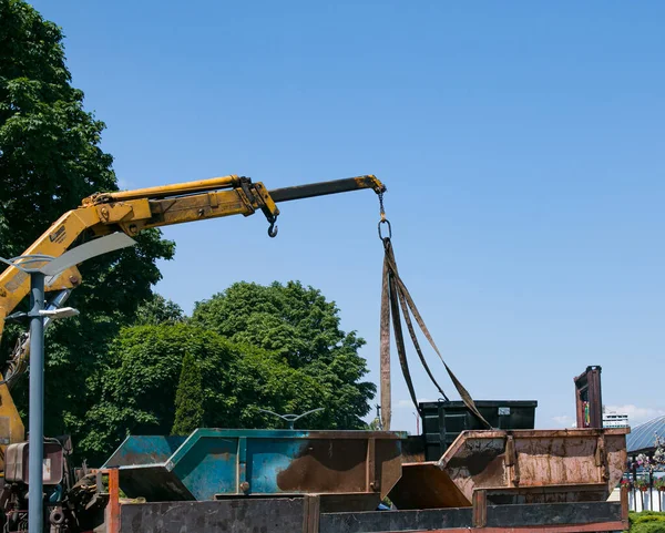 Çöp konteynırlarını vinç kullanarak bir kamyona yüklüyorlar. Slinger çalışıyor..