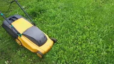 Elektrikli çim biçme makinesiyle çimleri biçmek. Erkek bahçıvan işini dışarıda yapıyor.