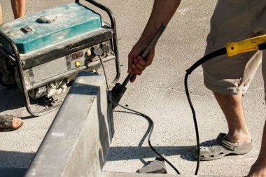 Kaldırım kaldırımının döşenme süreci. Bir işçi beton bloğu dairesel testere ile keser. Bir sürü toz..