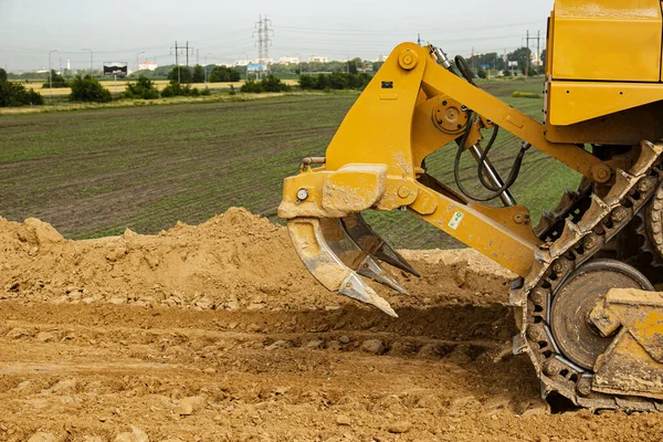 Asphalt road construction process. The bulldozer levels and compacts the clay soil for the base of the highway. Earthworks on a summer day.