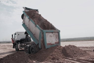 Dnepropetrovsk, Ukrayna - 06.26.2021: Yeni bir otoyol inşaatı için çöp kamyonu kil toprağı boşaltıyor. Yeni bir yolun temelini attığı için Clay..