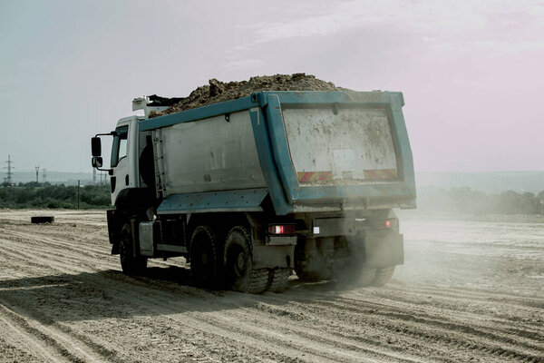 Dump truck unloads clay soil for the construction of a new highway. Clay for laying the foundation of a new road.