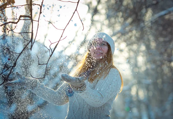 Happy woman plays with a snow in sunny winter day. Girl enjoys winter, frosty day. Playing with snow on winter holidays, a woman throws white, loose snow into the air. Walk in winter forest.