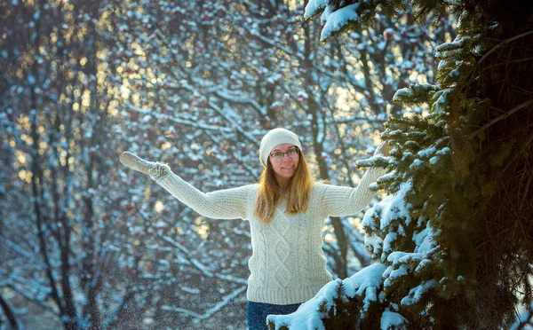 Happy woman plays with a snow in sunny winter day. Girl enjoys winter, frosty day. Playing with snow on winter holidays, a woman throws white, loose snow into the air. Walk in winter forest.