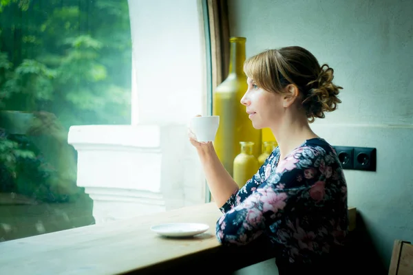 Stock image Morning coffee. Woman holding white Cup of black coffee sitting by the window. Young girl enjoys hot invigorating coffee in the morning