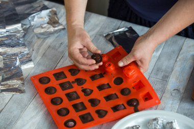 Adım adım, evdeki konyakta siyah çikolata ve kirazdan çikolata yapma süreci. Her bir şeker silikon kalıptan çıkartılır ve folyoya sarılır. Mutfak blogu kavramı.