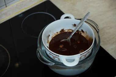 Adım adım, evdeki konyakta siyah çikolata ve kirazdan çikolata yapma süreci. Su banyosunda çikolatanın bileşenlerini eritme süreci. Mutfak blogu kavramı.