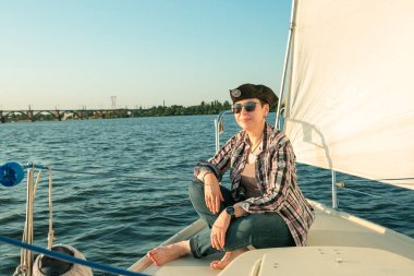 Lüks bir yat tatili. Tekne güvertesinde güneş gözlüklü mutlu orta yaşlı kadın nehirde yüzüyor..