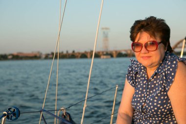 Lüks bir yat tatili. Tekne güvertesinde güneş gözlüklü mutlu orta yaşlı kadın nehirde yüzüyor..