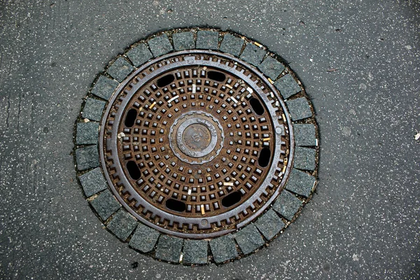 都市部のアスファルトの道路上の下水道マンホール 閉鎖写真 — ストック写真