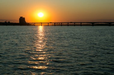 Dinyeper Nehri manzarası ve yatın yan tarafındaki köprü. Güneşin batışındaki şehir manzarası.
