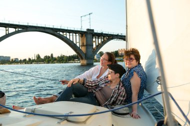 Lüks bir yat tatili. Mutlu orta yaşlı kadın kız arkadaş kayık güvertesinde nehirde yüzüyor.