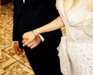 Gelin ve damadın elleri bir Katolik kilisesinde sunağın önünde. Düğün süreci.