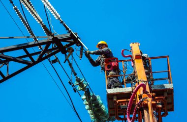 Dnepropetrovsk, Ukrayna - 08.06.2021: Vinç ve mavi gökyüzü ile yüksek voltajlı güç iletim kulesi işçileri. Patlayan asansörlerdeki hidrolik hattı çalışanları yüksek voltajlı elektrik hattı kuleleri üzerinde çalışıyorlar..