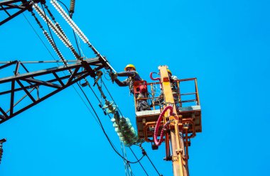 Dnepropetrovsk, Ukrayna - 08.06.2021: Vinç ve mavi gökyüzü ile yüksek voltajlı güç iletim kulesi işçileri. Patlayan asansörlerdeki hidrolik hattı çalışanları yüksek voltajlı elektrik hattı kuleleri üzerinde çalışıyorlar..