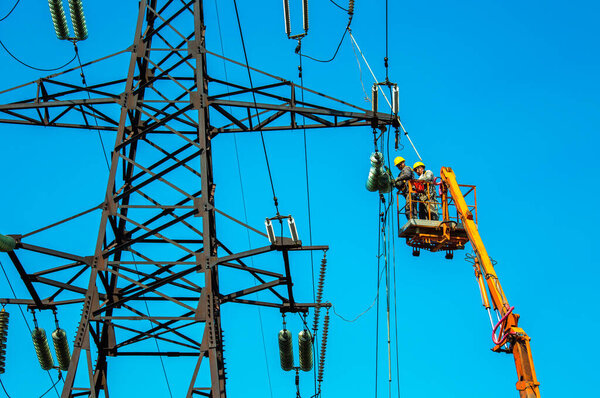 Днепропетровск, Украина - 08.06.2021: Работники ЛЭП с краном и голубым небом. Гиперлайнеры на стрелочных подъемниках работают на высоковольтных линиях электропередач.