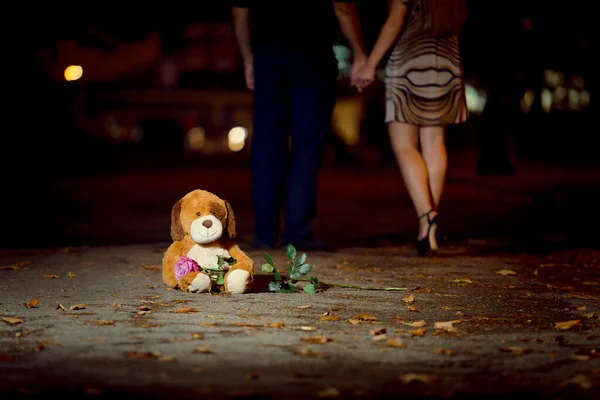 Medvídek Sedí Asfaltu Drží Čerstvou Růži Pozadí Nohou Milujícího Páru — Stock fotografie