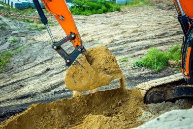 İnşaat alanındaki toprağı kazan kepçe kovası. Sürüngen kazıcı, yıkım alanında kazı yapıyor. Kazı makinesi. Toprak taşıma ekipmanı. Kazı aracı. İnşaat işi.
