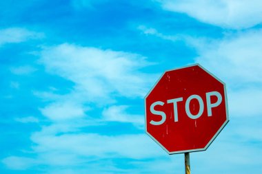 Mavi gökyüzüne karşı kırmızı trafik dur işareti. Bulutlu gökyüzünün arkaplanını imzala.