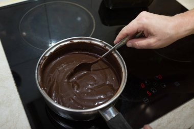 Çikolata jölesi yapma süreci. Adım adım. Malzemeler bir tencereye karıştırılmış. Erimek için yavaşça ısın..