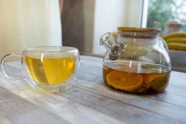 Masadaki cam çaydanlıkta naneli çay, çay ve dilimlenmiş limon. Naneli ve limonlu çay yapma süreci. Sağlıklı gıda konsepti.