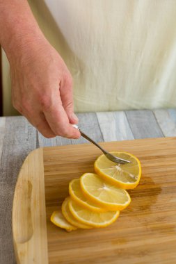 Bir kadın naneli ve çayla dilimlenmiş bir limonu çaydanlığa ekler. Naneli ve limonlu çay yapma süreci.