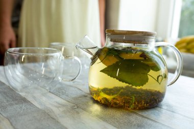 Masadaki cam çaydanlıkta naneli çay, çay ve dilimlenmiş limon. Naneli ve limonlu çay yapma süreci. Sağlıklı gıda konsepti.
