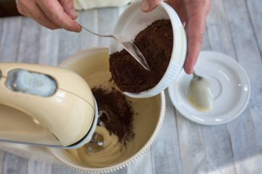 Pasta yapma süreci. Kadın eli, hamur yapmak için karıştırma kabına kakao ekler. Adım adım çikolatalı pasta tarifi. Seriler. Pişirme kavramı.