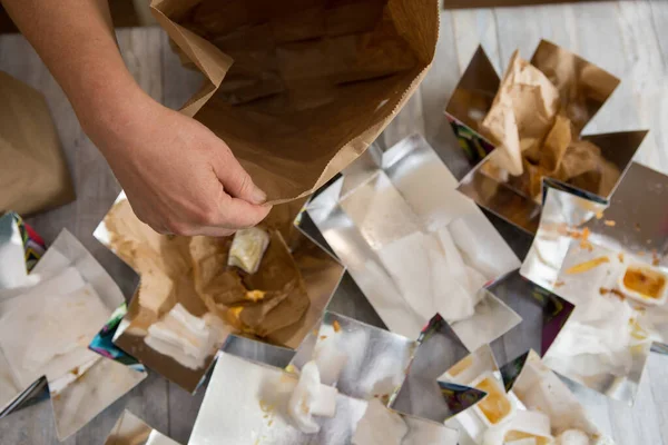 Female hands are wrapping paper bags from delivered food. Waste paper is placed in separate paper waste bins for recycling.