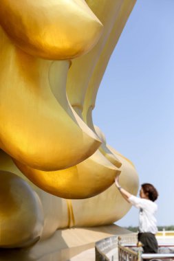 Kimliği belirsiz kadın elini büyük bir Buda dokunmadan dua 