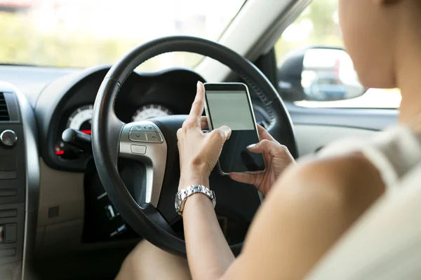 Mujer sentada en el coche utilizar mensajes de texto del teléfono móvil durante la conducción —  Fotos de Stock