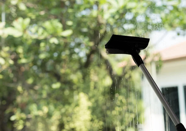 Limpiador de ventanas usando una escobilla para lavar un windo — Foto de Stock