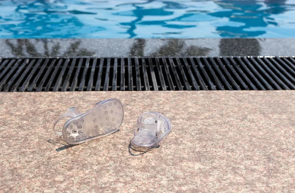 Pareja de chanclas de bebé sentadas en un lado de la piscina — Foto de Stock