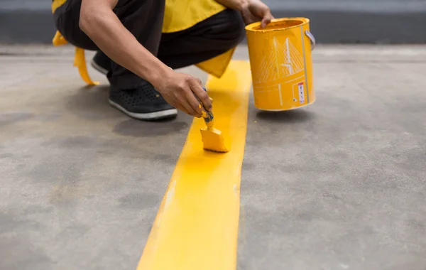 Hombre pintando la línea amarilla en el suelo de hormigón —  Fotos de Stock