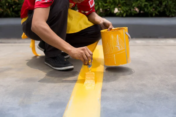 Hombre pintando la línea amarilla en el suelo de hormigón — Foto de Stock