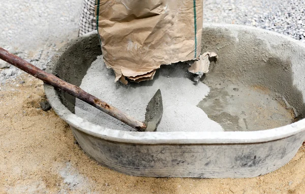 Trabalhador derramando cimento em pó na bandeja de mistura — Fotografia de Stock