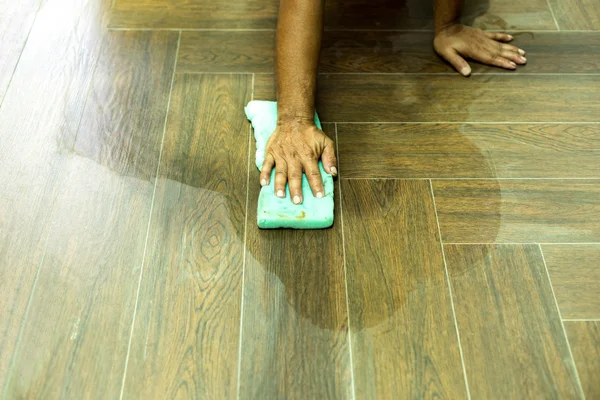 Worker cleaning floor tile after grouting tiles with sponge