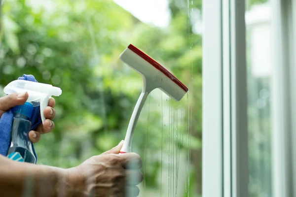 Mão segurando janela de limpeza escova com detergente spray — Fotografia de Stock