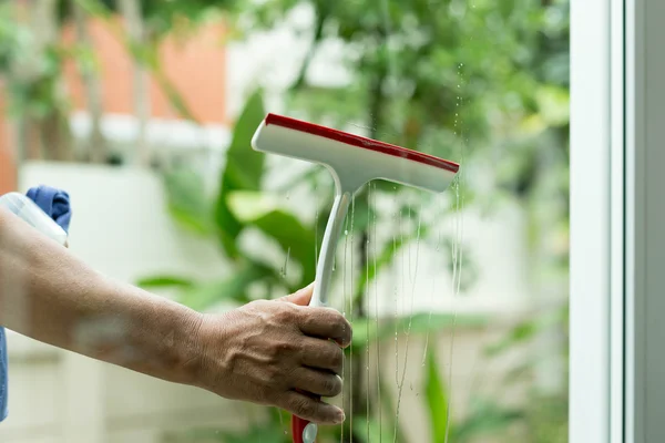 Vrouw reinigen van ramen met spray wasmiddel — Stockfoto