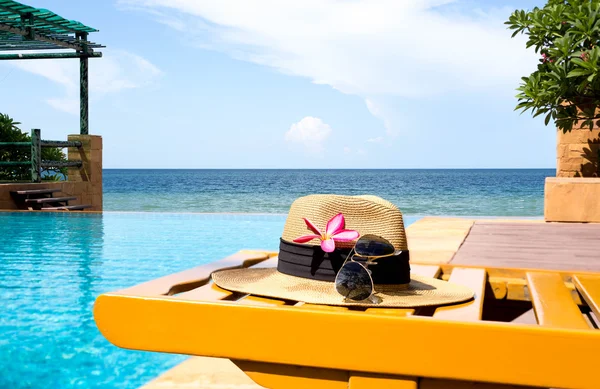 Óculos de sol e chapéu e piscina com flor e mar — Fotografia de Stock