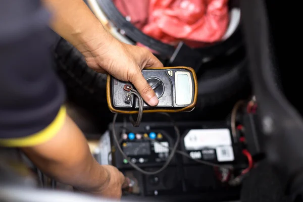 Mecânico verificando o nível da bateria de um carro com voltímetro — Fotografia de Stock