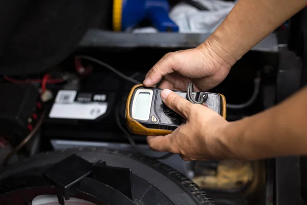 Mecânico verificando o nível da bateria de um carro com voltímetro — Fotografia de Stock