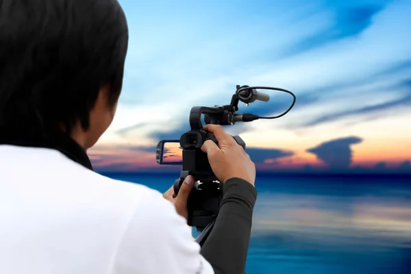 Uomo che registra il tramonto sull'oceano con registratore vedio — Foto Stock