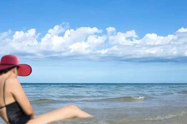 Mujer borrosa en sombrero de playa rosa relajante en el mar —  Fotos de Stock