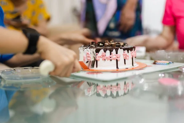 Woman is hand cutting birthday cake together with family