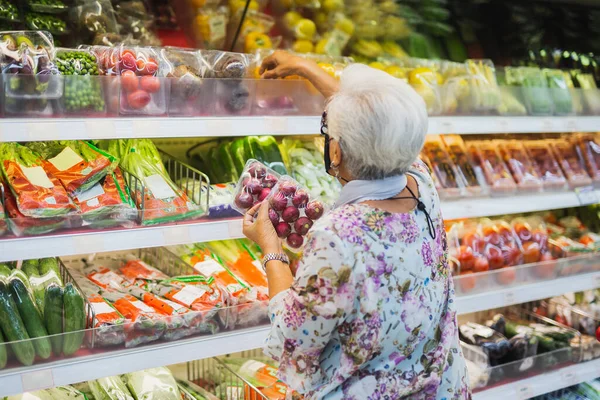 Senior woman wearing protective mask doing grocery shopping in supermarket